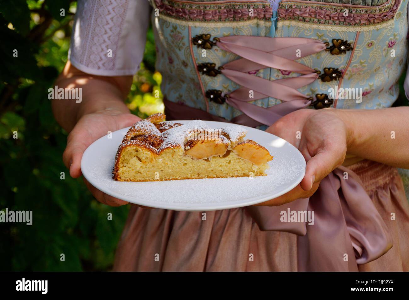 Une femme dans une belle robe traditionnelle de dirndl tenant un morceau de tarte aux pommes maison délicieuse à la fête bavaroise d'octobre (Oktoberfest) (Bavière, Banque D'Images