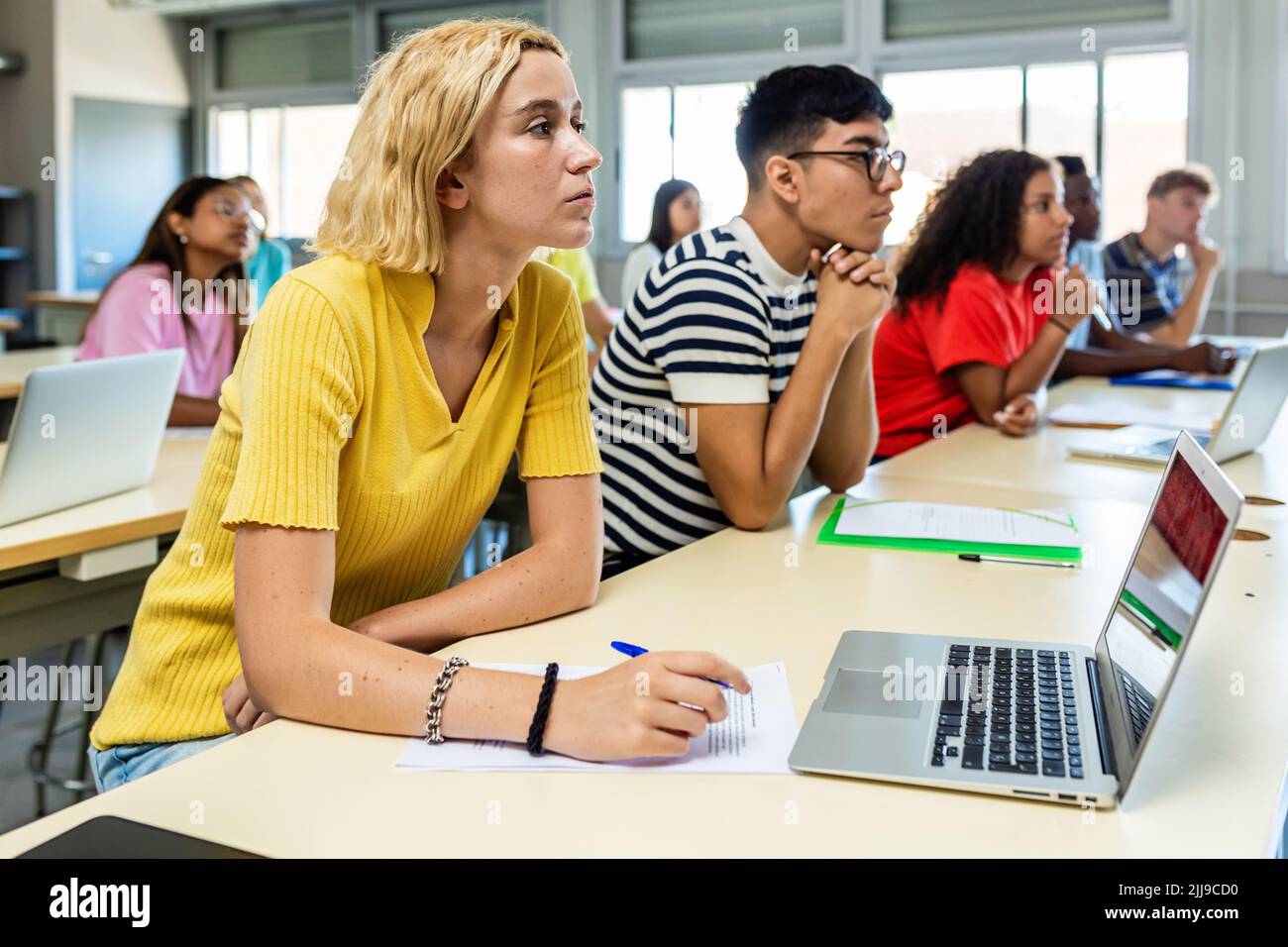 Groupe d'élèves multiethniques écoutant le professeur en classe à l'école secondaire Banque D'Images