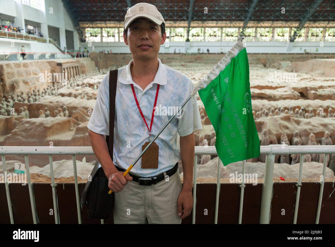 Guide touristique avec un drapeau aux couleurs vives qui mène à une fête de touristes chinois visitant / observant le stand 1 de l'armée de terre cuite au musée du Mausolée de l'empereur Qinshihuang à Xi'an, en Chine. PRC. (125) Banque D'Images