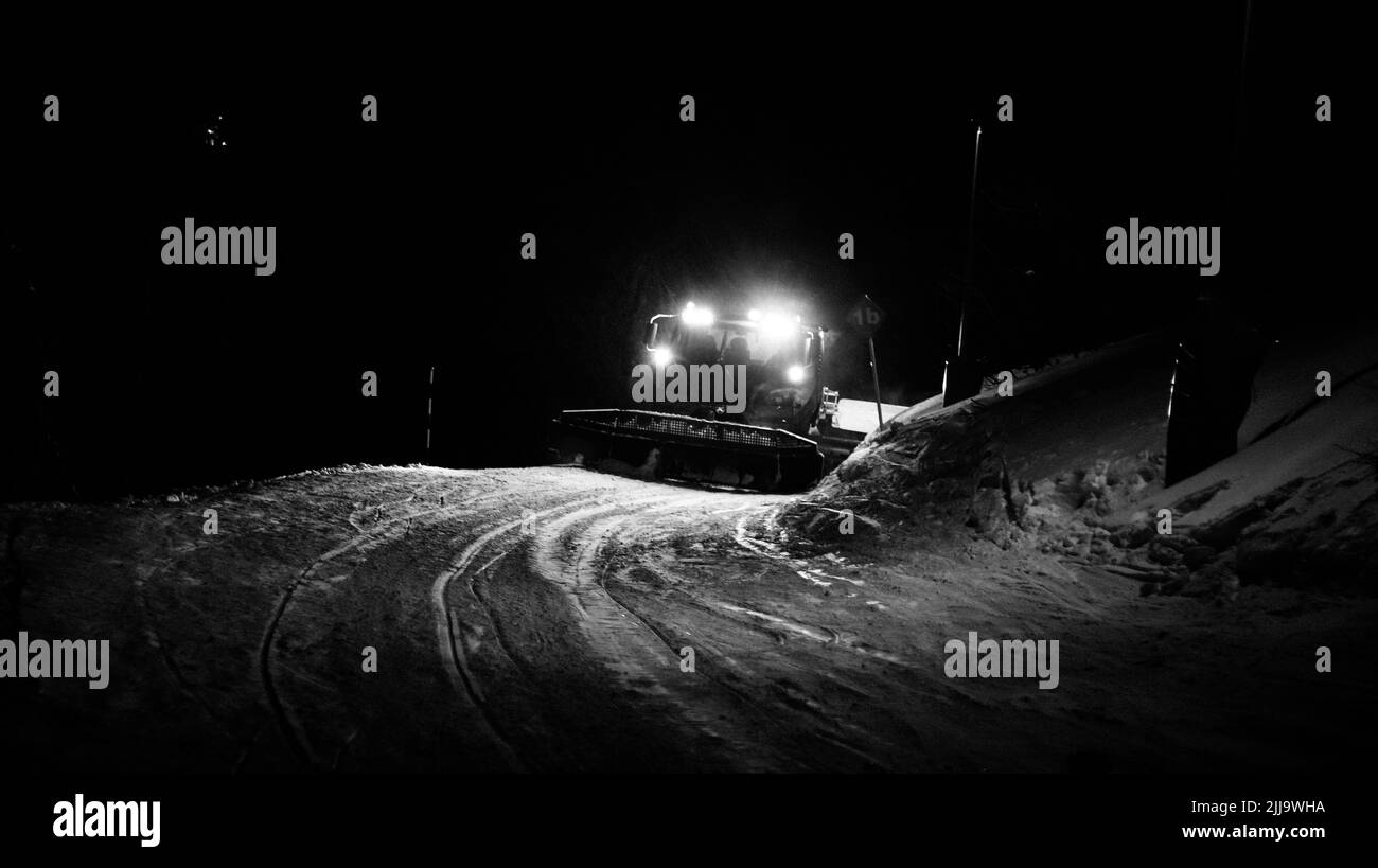 Un véhicule Snowmobile spécial pour le nettoyage des tronçons enneigés des routes de montagne, labourant la nuit. Banque D'Images