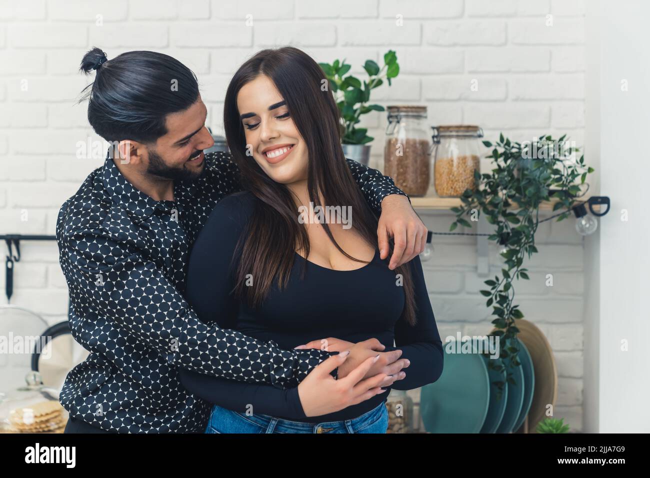 Une femme caucasienne aux cheveux longs dit à son beau partenaire barbu dans une chemise noire à motifs qu'elle est enceinte. Bonne nouvelle. Intérieur de la cuisine. Photo de haute qualité Banque D'Images