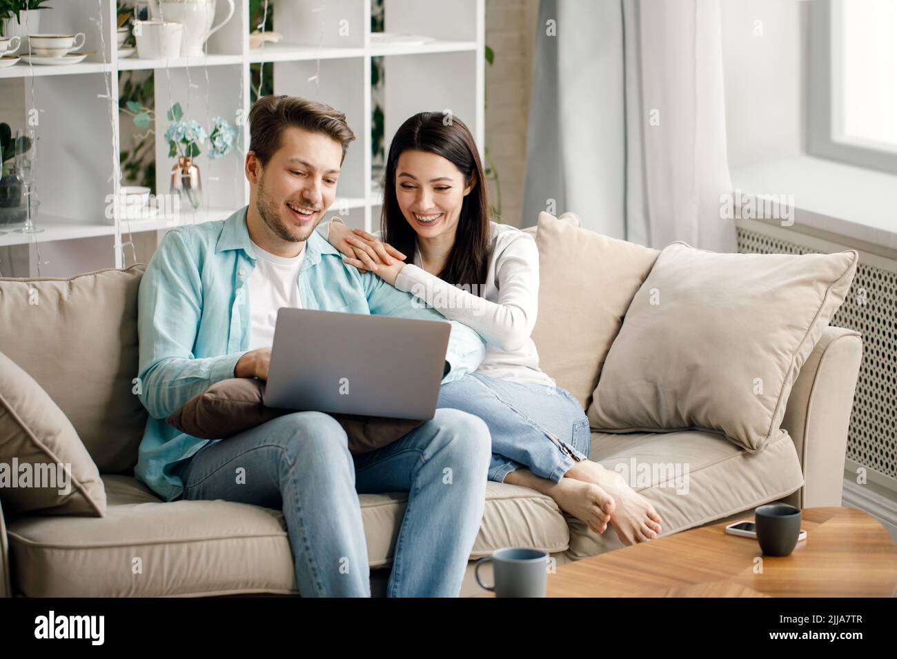 Les jeunes couples apprécient la téléconférence sociale avec leur famille via l'écran d'ordinateur portable dans la distance sociale de condominium Banque D'Images