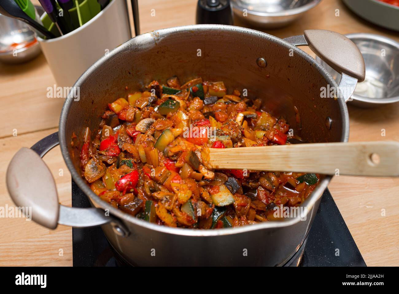 faire sauter des légumes dans une casserole sur une cuisinière électrique avec une spatule en bois. vue de dessus de la table de cuisine. Banque D'Images