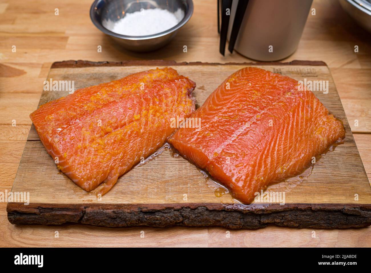 Deux filets de saumon marinés dans de la pulpe d'orange sur une planche de bois avant la cuisson. Banque D'Images