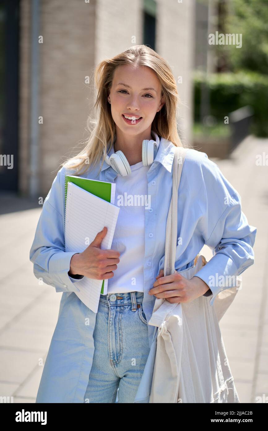 Jolie fille souriante étudiant d'université debout à l'extérieur, portrait vertical. Banque D'Images