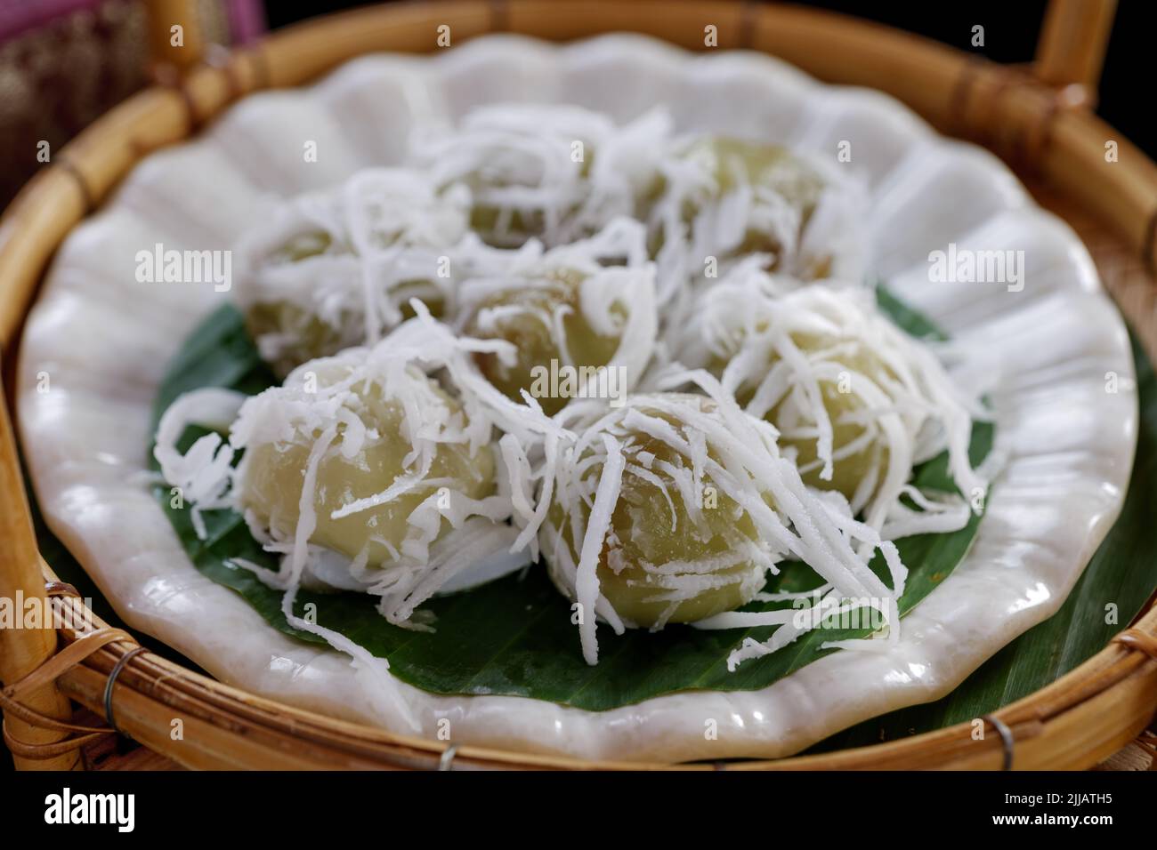 Boules de noix de coco thaïlandaises, Kha Nom Tom, sur plaque blanche et panier en rotin. Banque D'Images