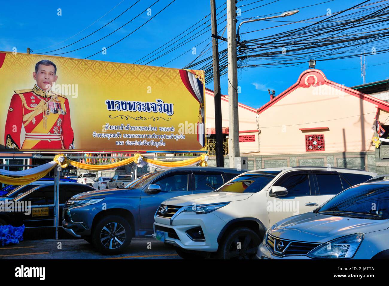 Un grand portrait du roi thaïlandais Maha Chulalongkorn, Rama X., surplombe un parking devant un temple taoïste-chinois dans la ville de Phuket, en Thaïlande Banque D'Images