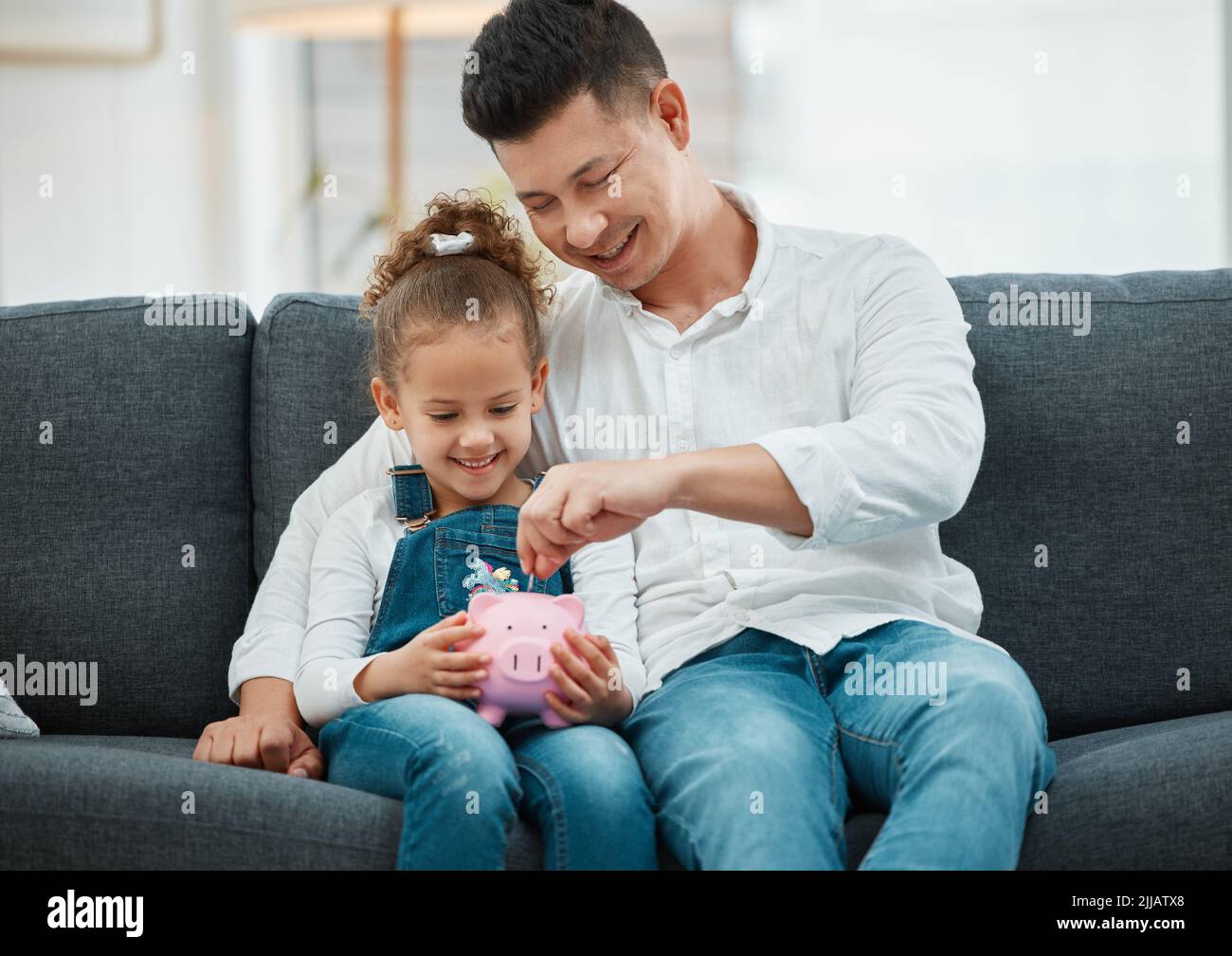 Soyez intelligent en investissant. Un père enseignant à sa fille de sauver dans une porcgybank. Banque D'Images