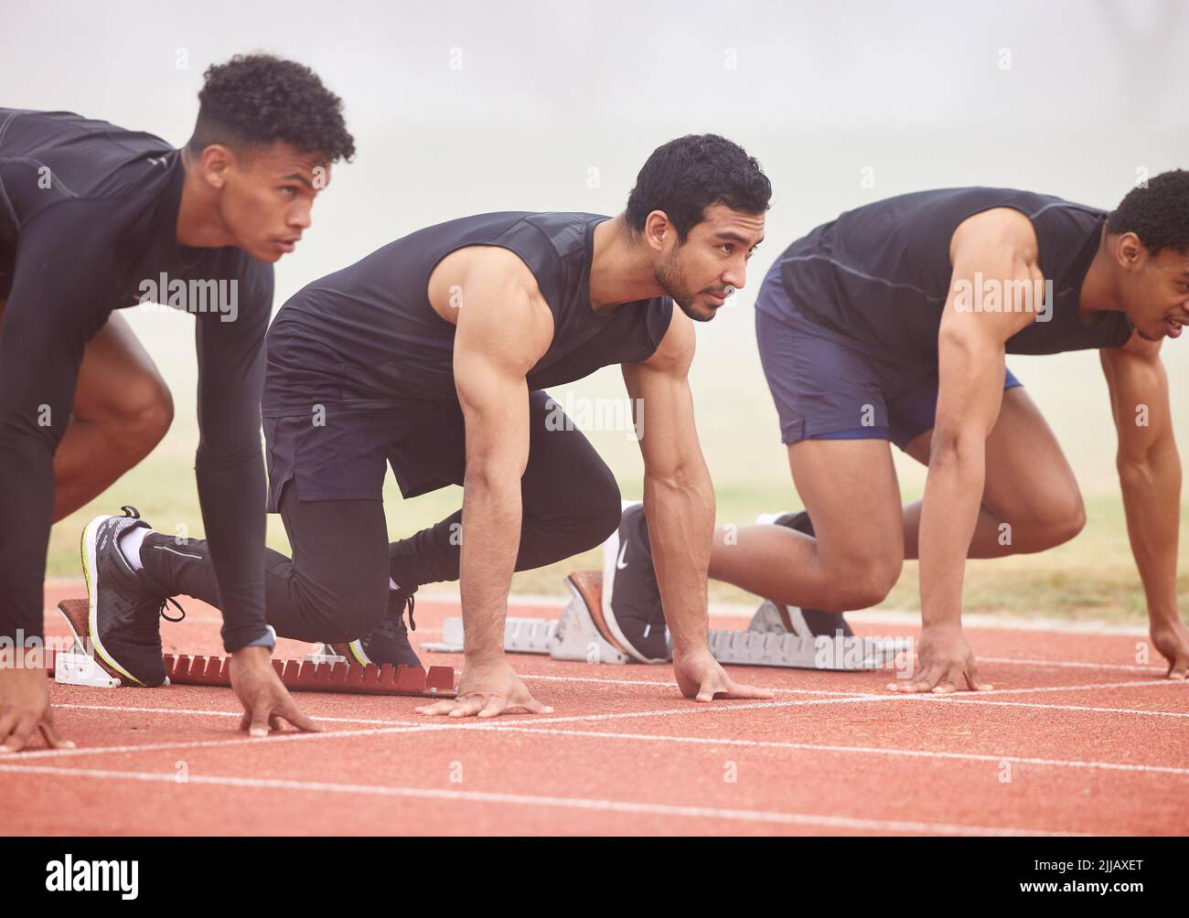 Prêt à commencer. Trois jeunes athlètes masculins de haut niveau commencent leur course sur une piste. Banque D'Images