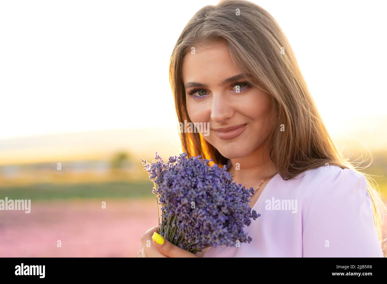 Gros plan portrait d'une jeune femme tenant un bouquet de lavande blaniile debout dans le champ de lavande Banque D'Images