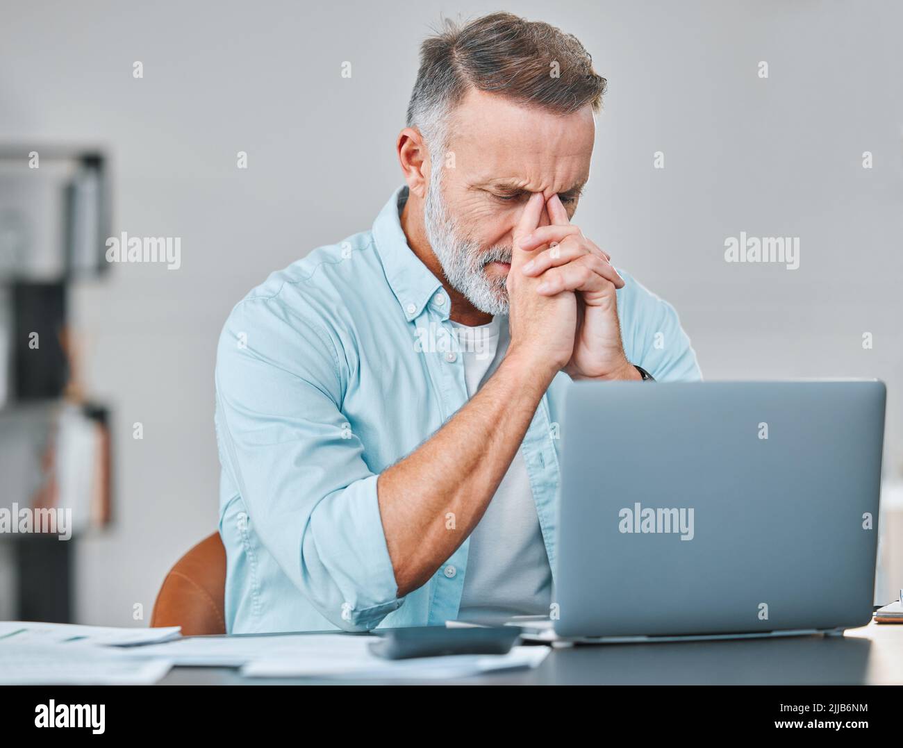 Pas encore. Un homme d'affaires mature assis seul dans son bureau et se sentant stressé en utilisant son ordinateur portable. Banque D'Images