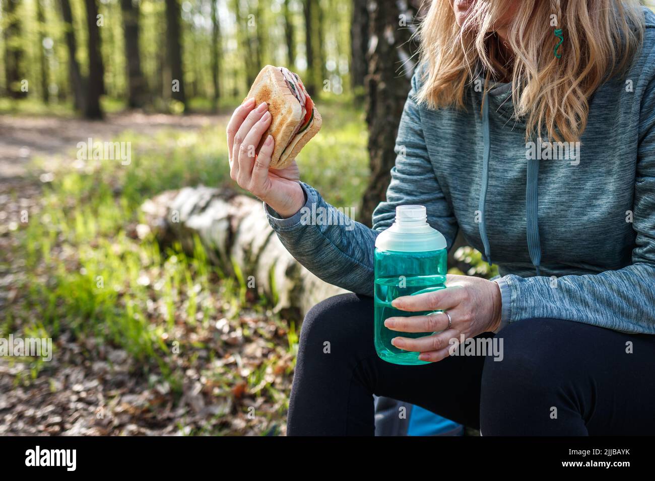 Femme mangeant un sandwich et de l'eau potable à l'extérieur. Rafraîchissements pendant la randonnée en forêt. Femme touriste se reposer et camper dans les bois Banque D'Images
