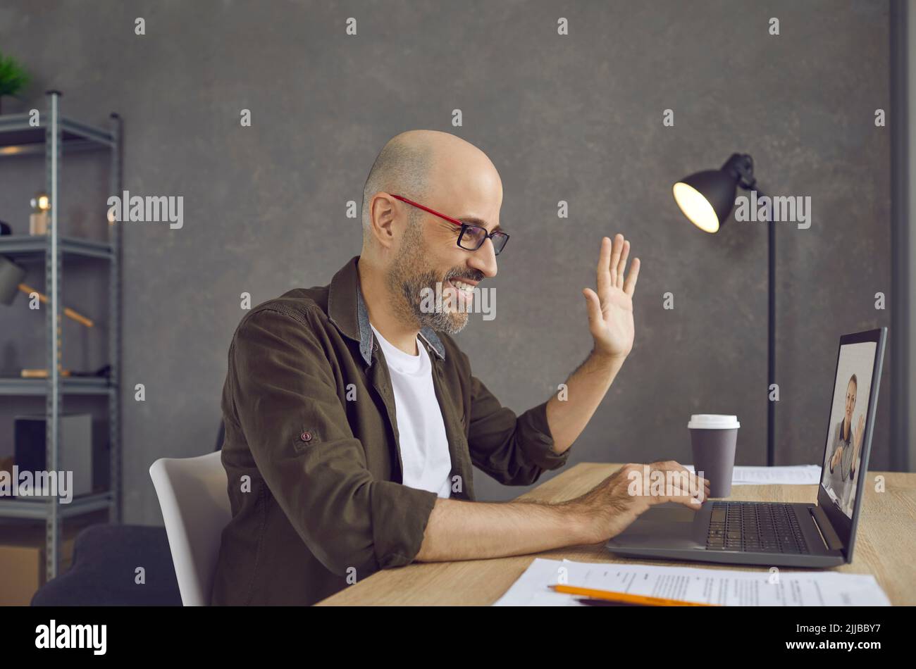 Homme qui commence une réunion d'affaires virtuelle et qui se fait un bonjour à l'écran d'un ordinateur portable Banque D'Images