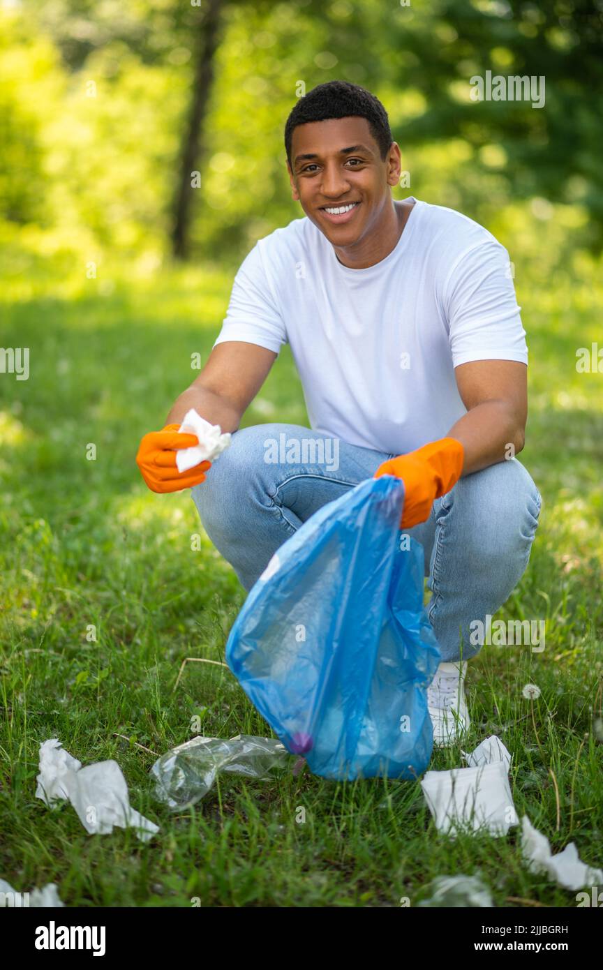 Homme ramassant les déchets de papier souriant à l'appareil photo Banque D'Images