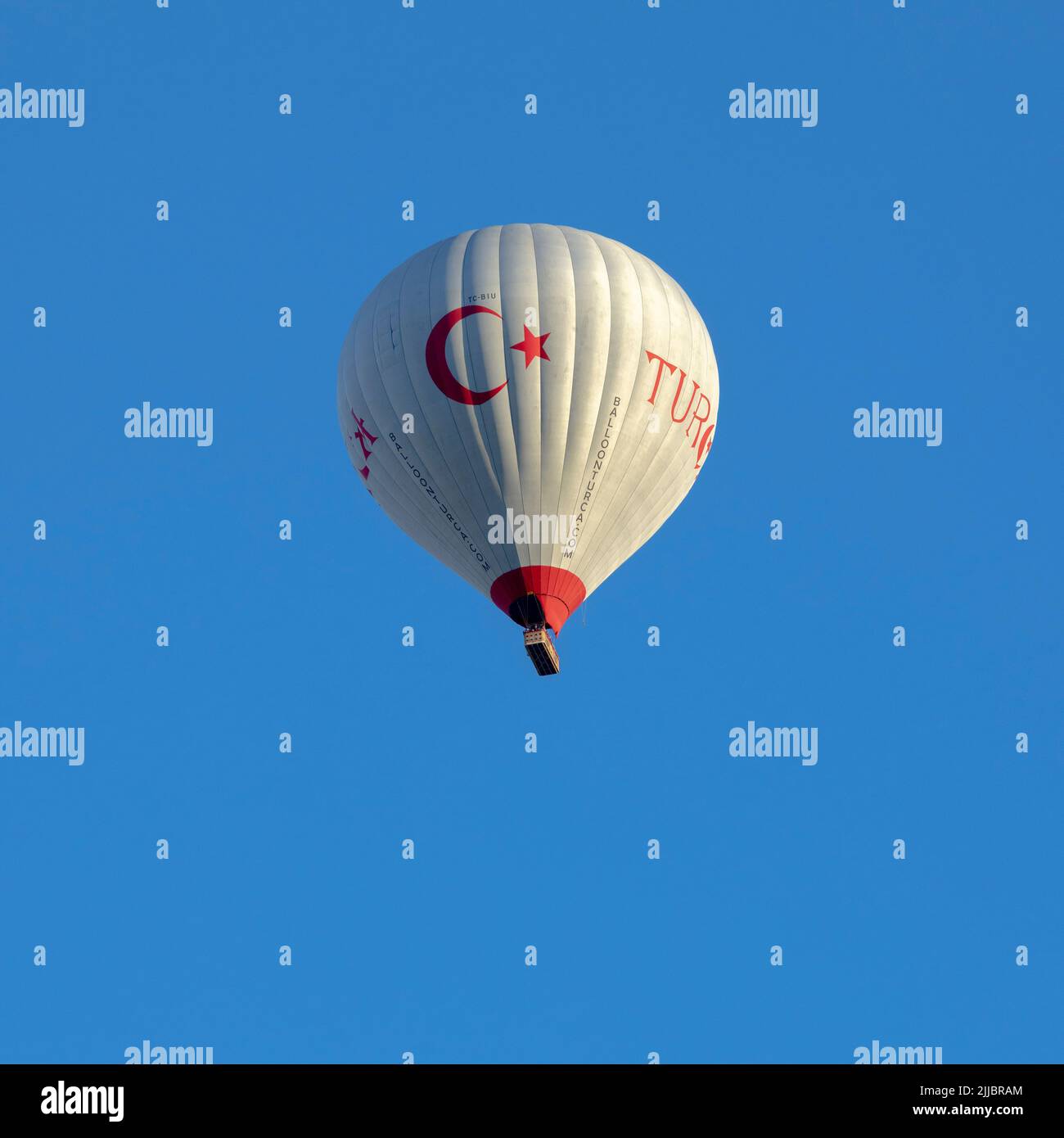 GÖREME/TURQUIE - 27 juin 2022: Ballon d'air chaud avec drapeau de la turquie vole dans le ciel bleu Banque D'Images