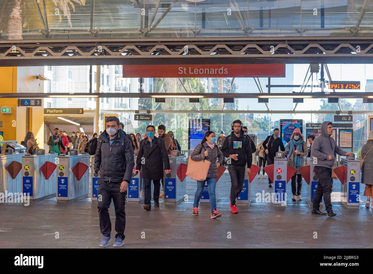 Certains portent des masques à l'aide de leur carte opale pour passer par les portes d'entrée à la gare St Leonards, un matin d'hiver à Sydney, en Australie Banque D'Images