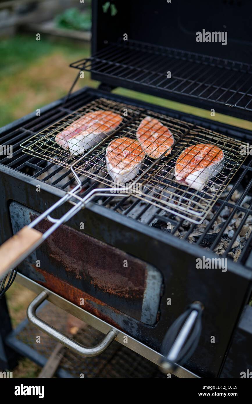 les steaks de saumon sur le grill sont cokking sur le bois de chauffage dans l'arrière-cour. Banque D'Images
