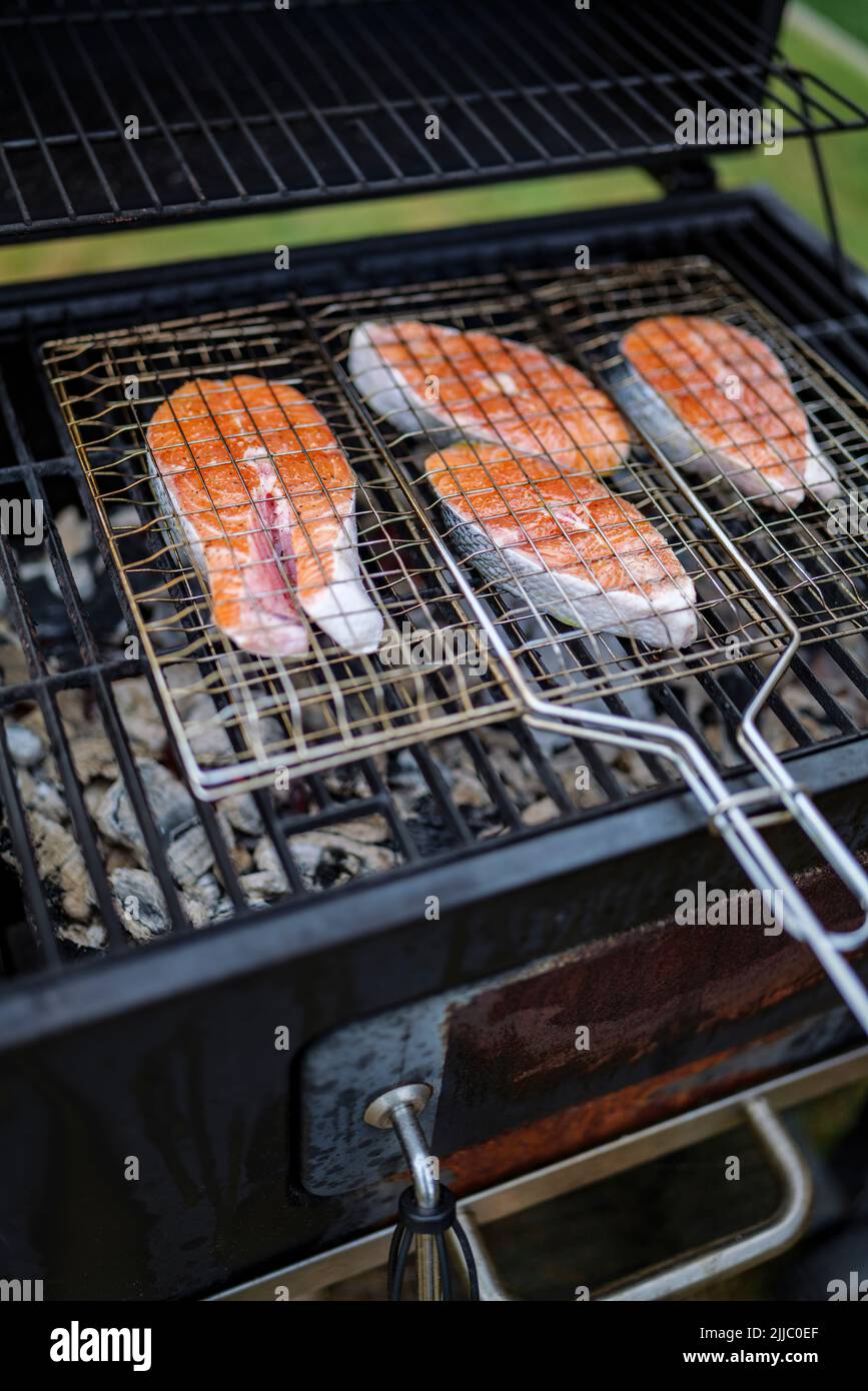 les steaks de saumon sur le grill sont cokking sur le bois de chauffage dans l'arrière-cour. Banque D'Images