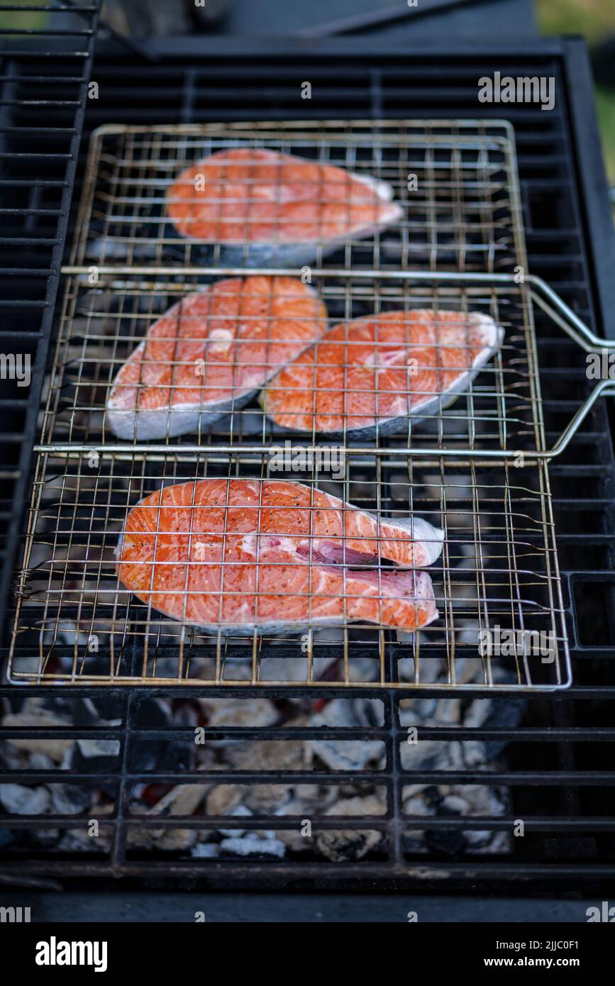 les steaks de saumon sur le grill sont cokking sur le bois de chauffage dans l'arrière-cour. Banque D'Images