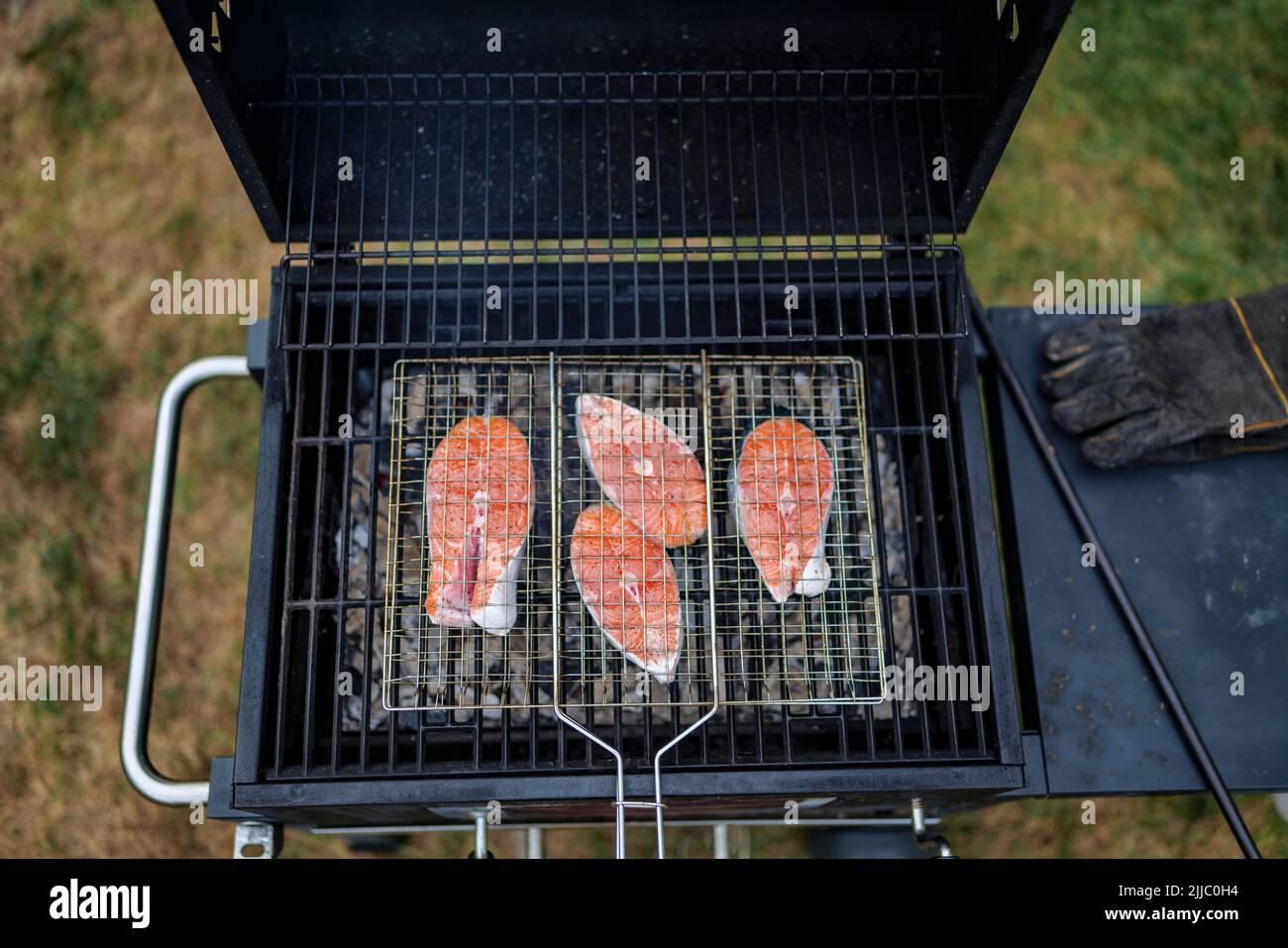 les steaks de saumon sur le grill sont cokking sur le bois de chauffage dans l'arrière-cour. Banque D'Images