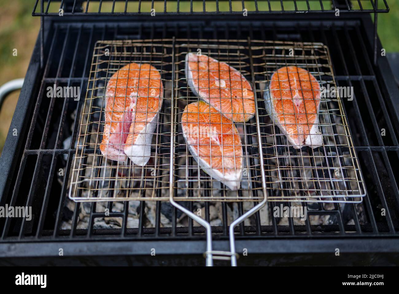 les steaks de saumon sur le grill sont cokking sur le bois de chauffage dans l'arrière-cour. Banque D'Images