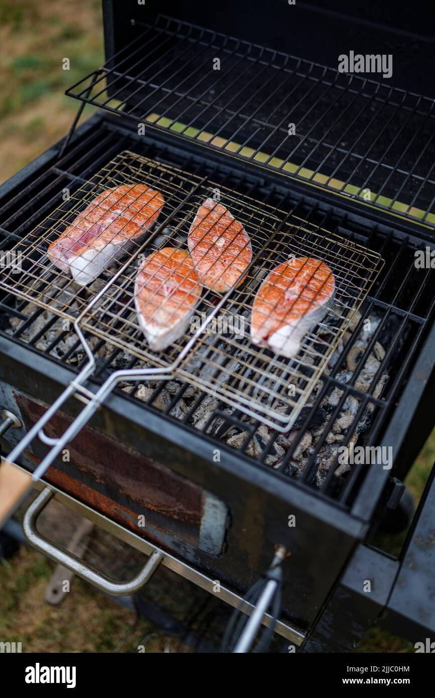 les steaks de saumon sur le grill sont cokking sur le bois de chauffage dans l'arrière-cour. Banque D'Images