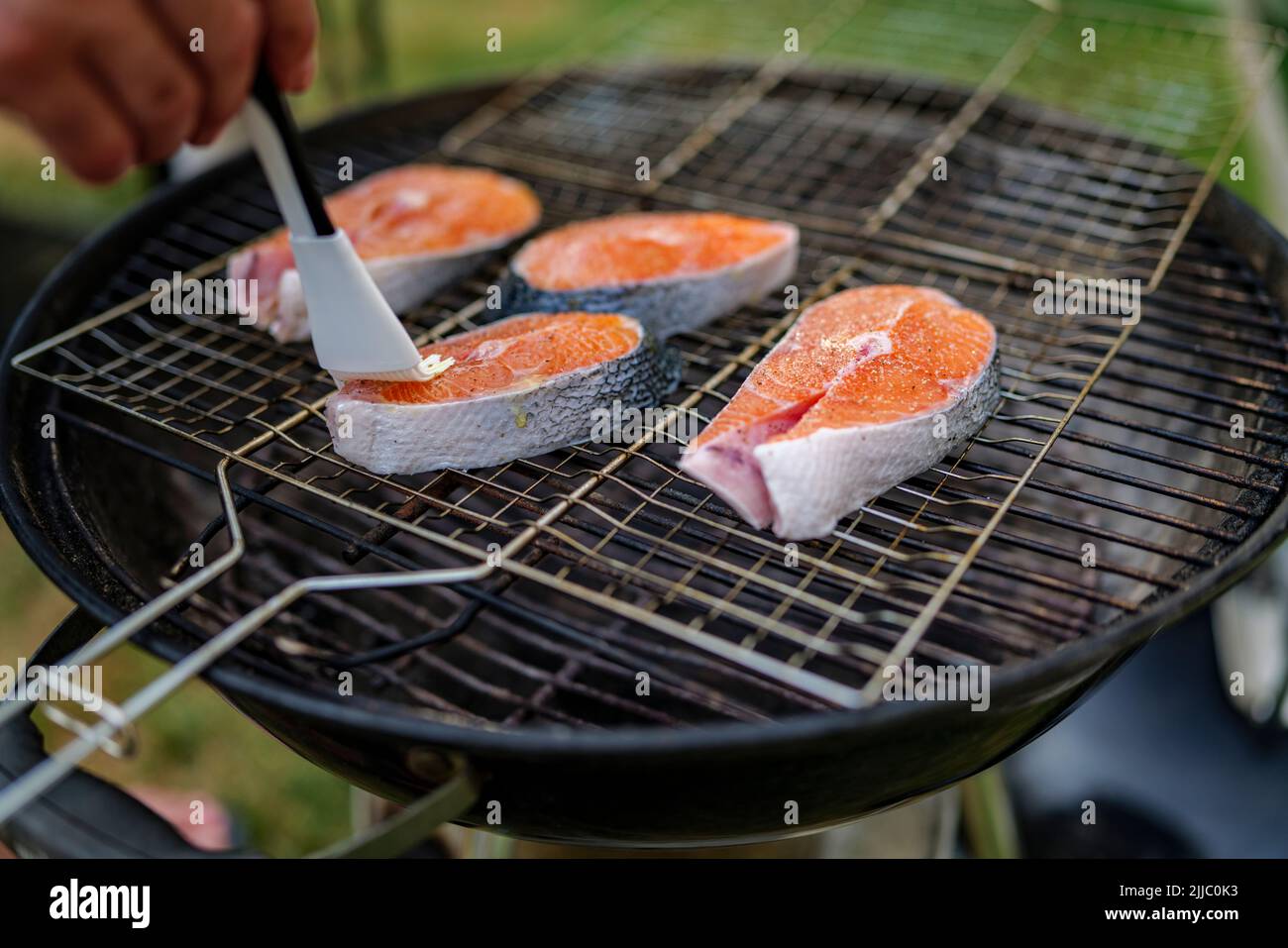 Gros plan de steak de saumon frais huilé préparé pour griller avec des grains de sel dessus, repose sur le filet du gril Banque D'Images