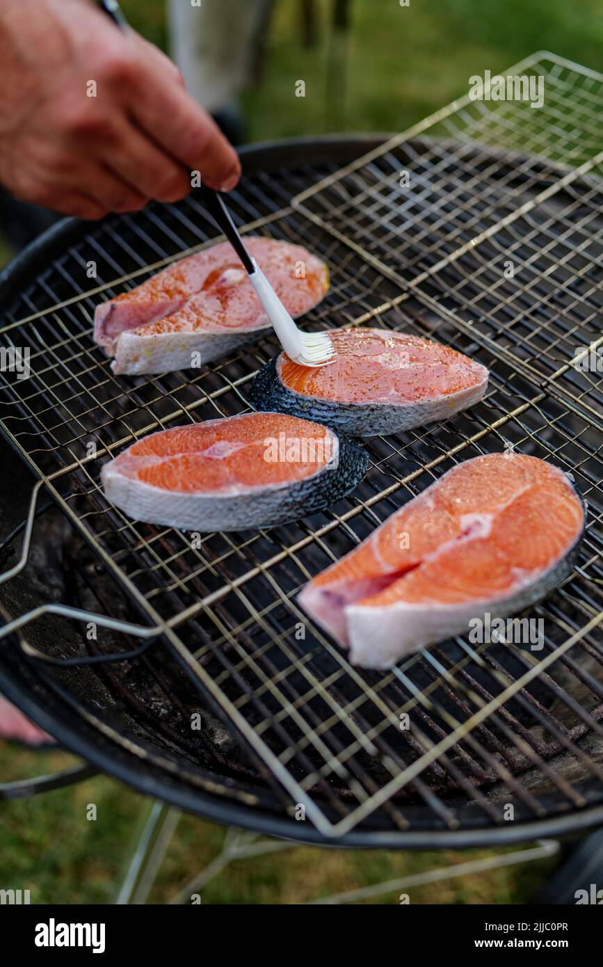 Gros plan de steak de saumon frais huilé préparé pour griller avec des grains de sel dessus, repose sur le filet du gril Banque D'Images