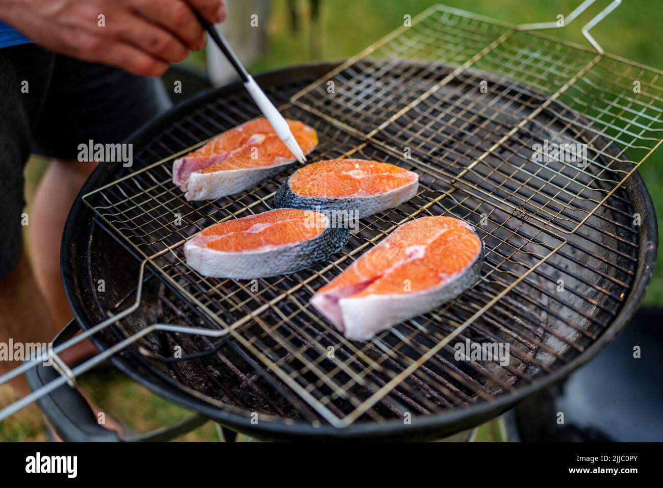 Gros plan de steak de saumon frais huilé préparé pour griller avec des grains de sel dessus, repose sur le filet du gril Banque D'Images