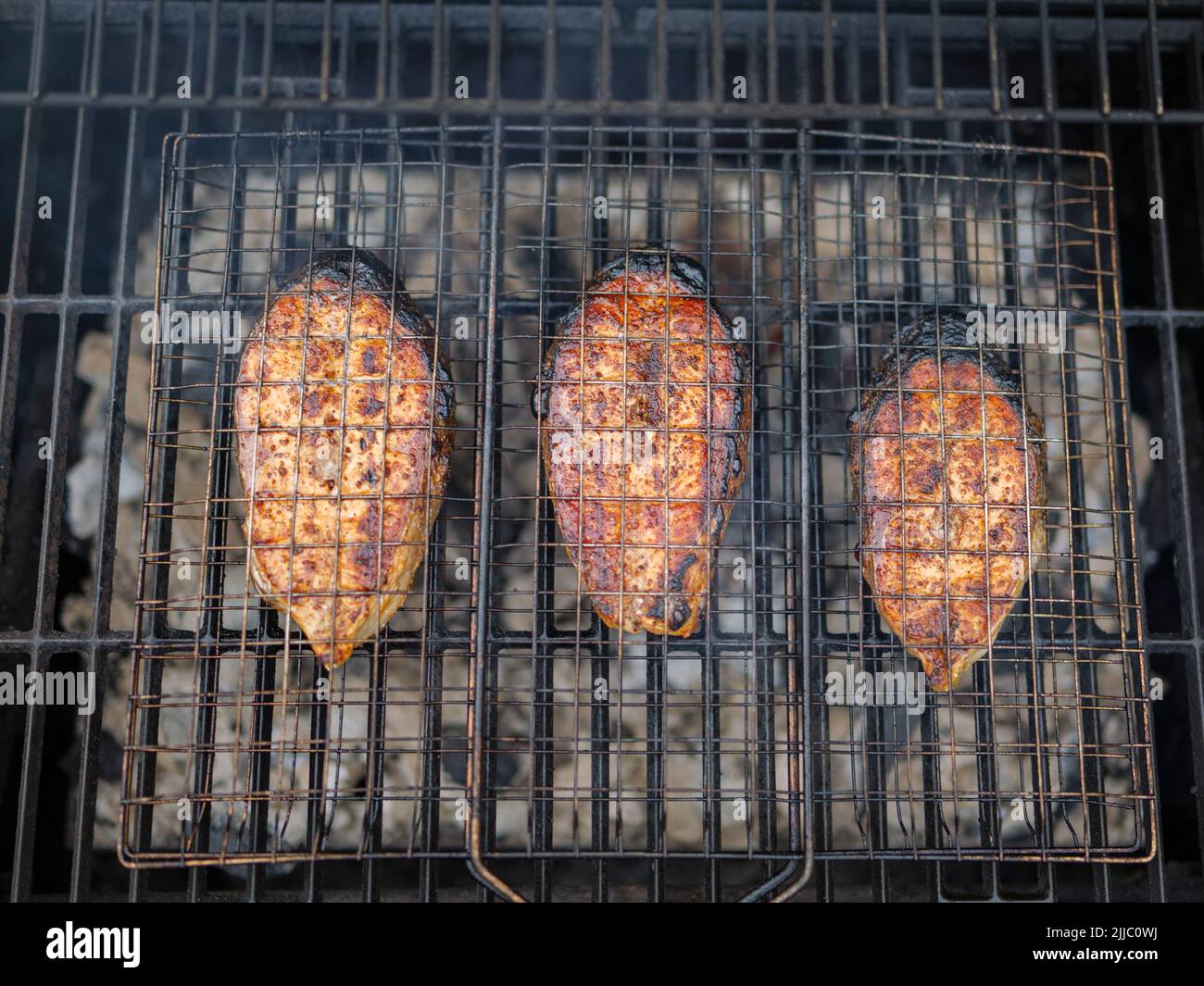 les steaks de saumon sur le grill sont cokking sur le bois de chauffage dans l'arrière-cour. Banque D'Images