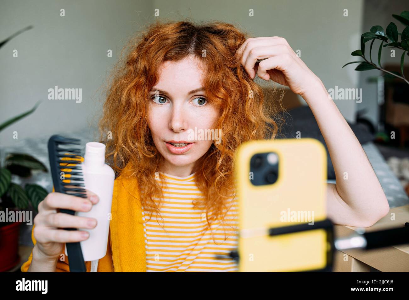 La blogueur de femme à cheveux rouges diffuse des critiques en direct de produits de beauté pour les cheveux Banque D'Images