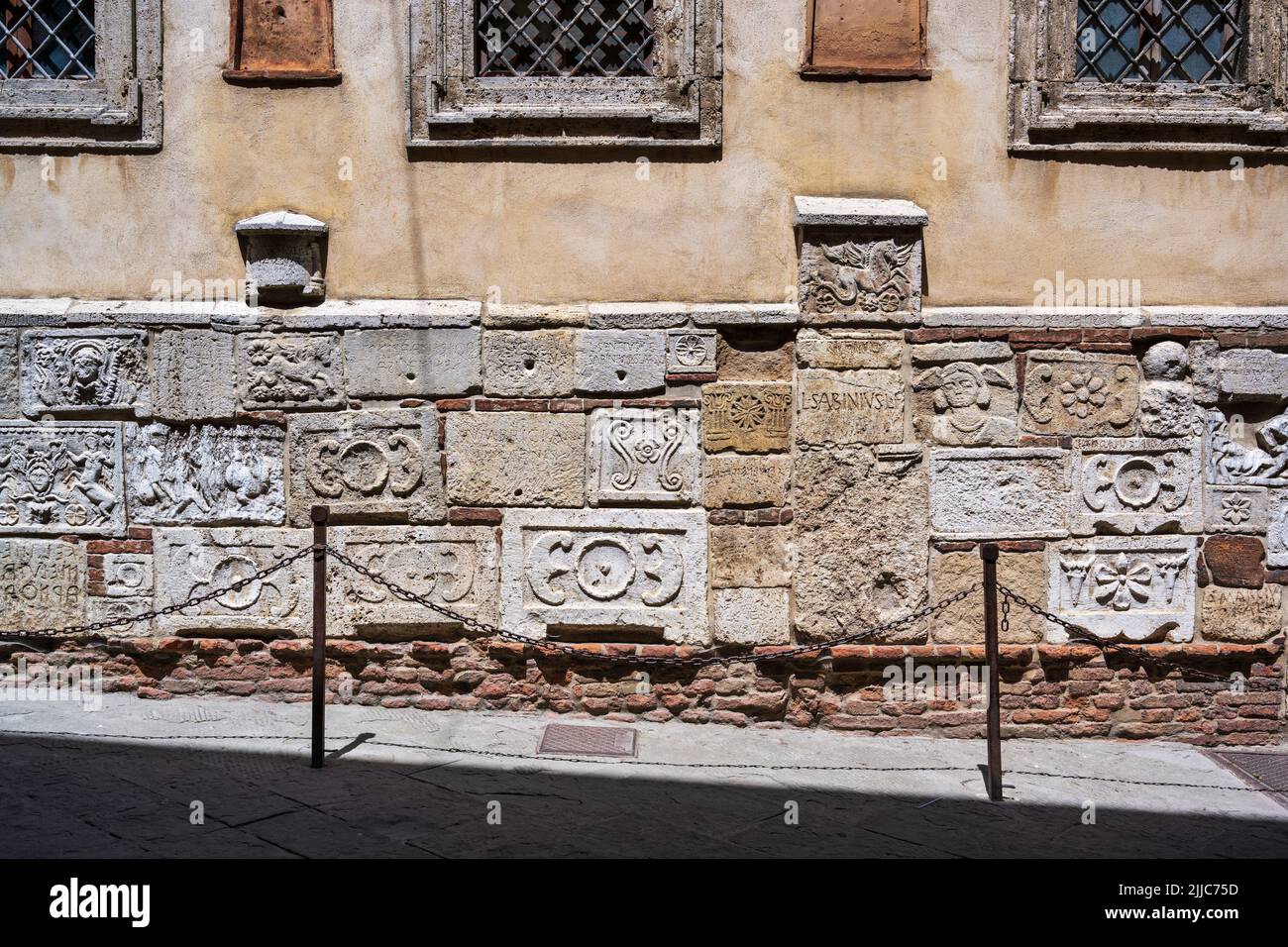 Anciens reliefs étrusques et urnes funéraires sur la façade inférieure du Palazzo Bucelli sur la via di Gracciano Nel Corso à Montepulciano, Toscane, Italie Banque D'Images