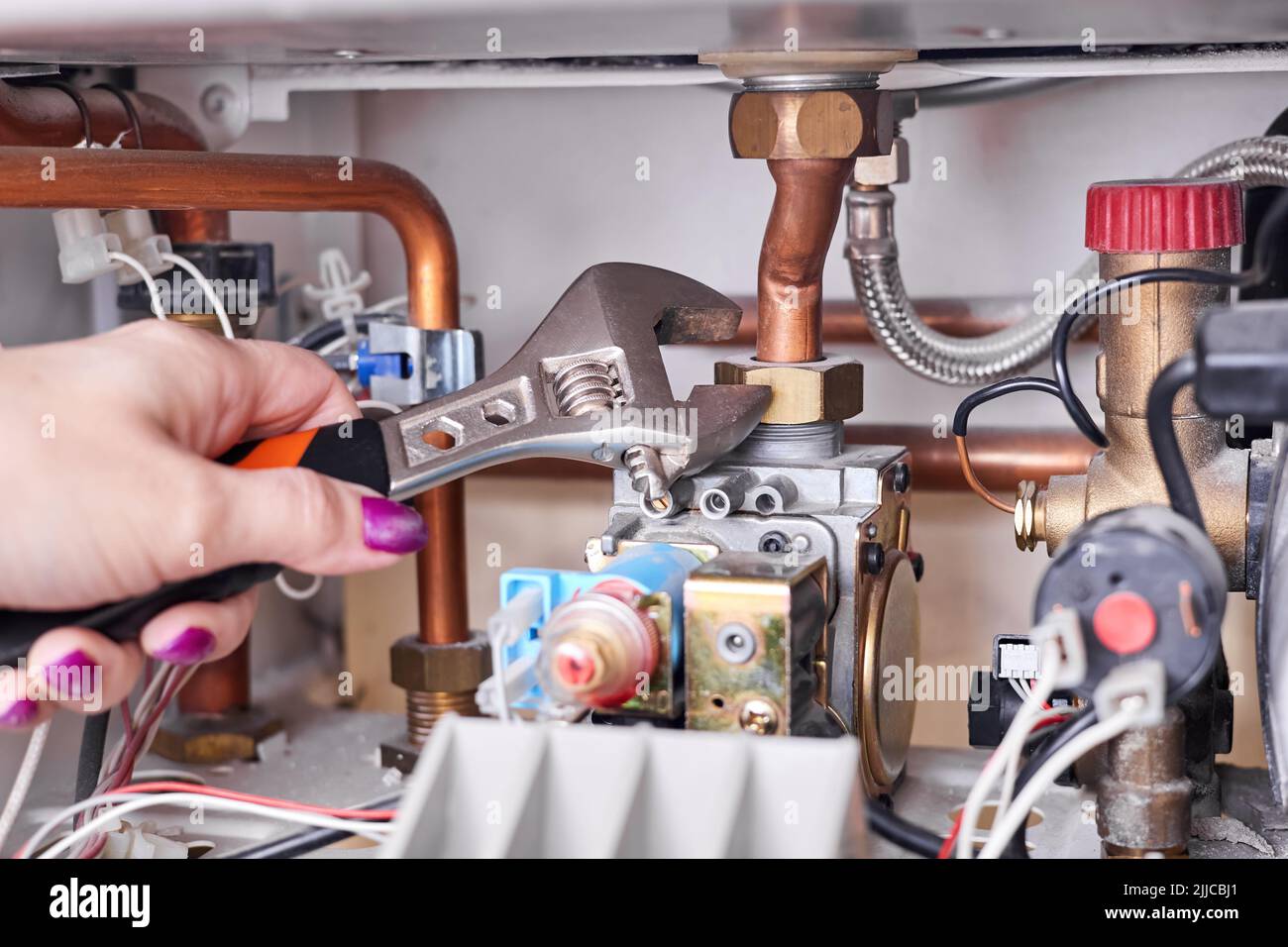 La fille va réparer la chaudière à gaz à l'aide d'une clé réglable Photo  Stock - Alamy