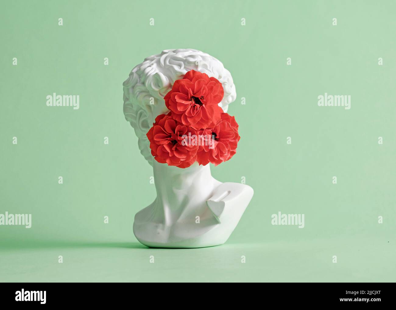 Sculpture de la tête de David de Michel-Ange avec fleur de rose à visage fermé. Concept minimaliste de pastel créatif incognito et furtif. Banque D'Images