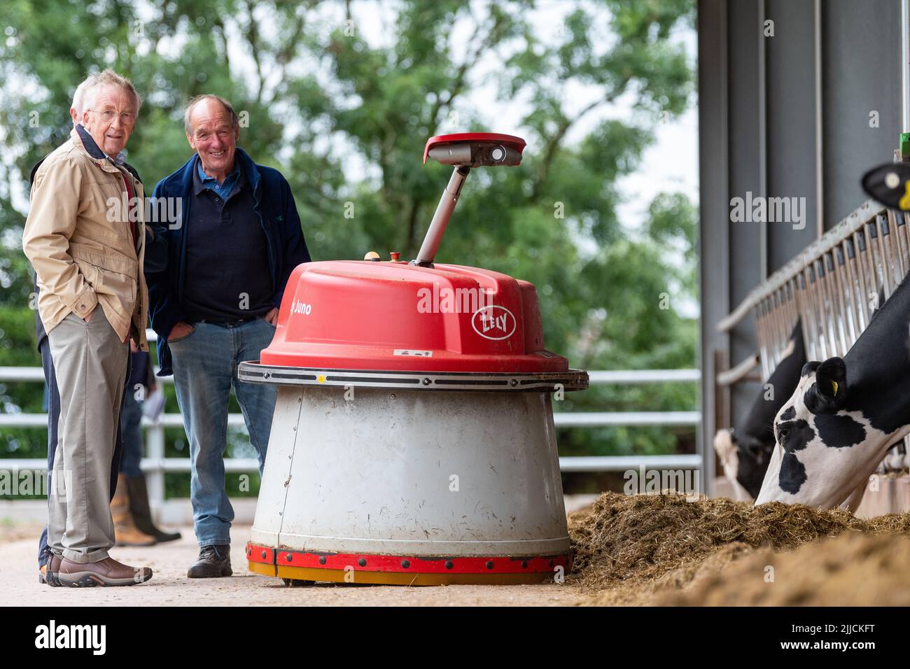 Un groupe d'agriculteurs regardant un robot pousser l'ensilage vers le haut pour que le bétail laitier puisse mieux manger. Dumfries, Royaume-Uni. Banque D'Images