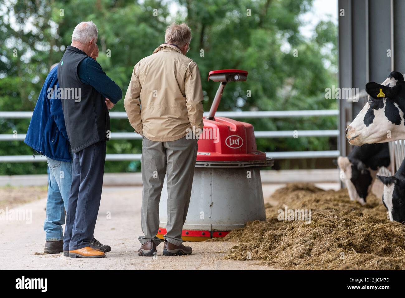 Un groupe d'agriculteurs regardant un robot pousser l'ensilage vers le haut pour que le bétail laitier puisse mieux manger. Dumfries, Royaume-Uni. Banque D'Images
