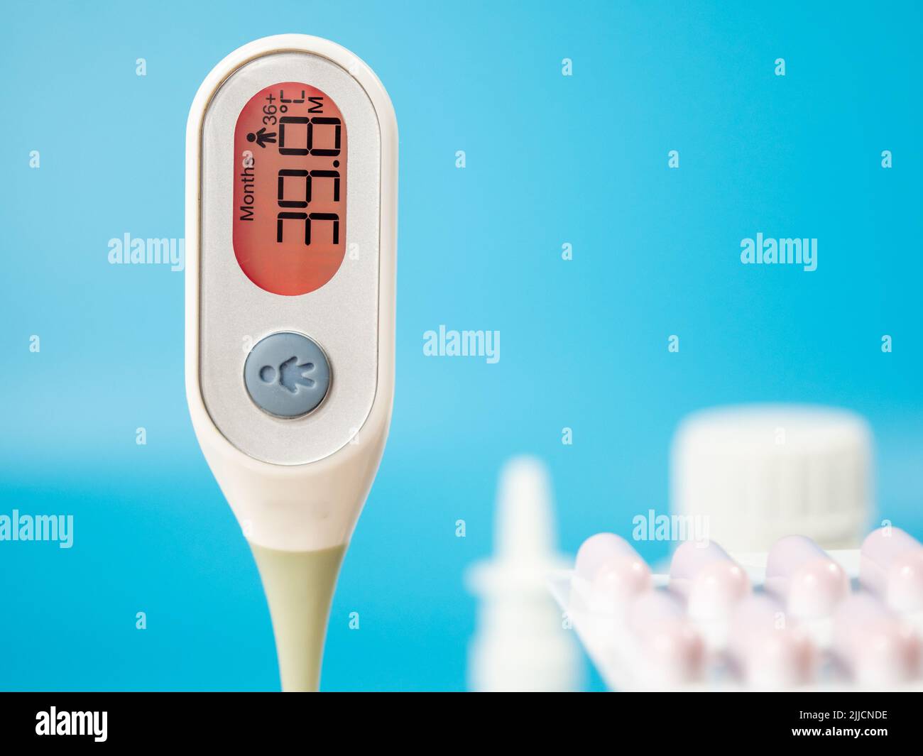 Le thermomètre pour mesurer la température du corps indique une température élevée. Thermomètre numérique médical et médicaments sur fond bleu. Banque D'Images