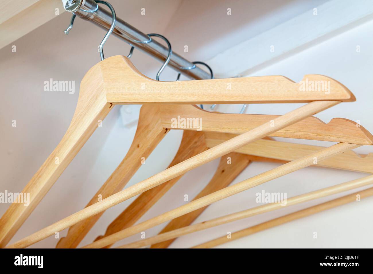 Cintres en bois suspendus sur un rail en métal à l'intérieur d'un placard. Banque D'Images