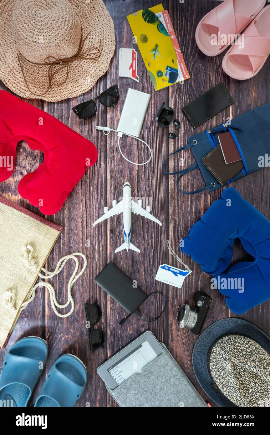 L'homme et la femme couplez des accessoires de vacances sur les planches de bois sombre. Chapeaux de voyage, appareil photo, lunettes, porte-étiquettes, tongs, lecteur, sac de plage, avion f Banque D'Images