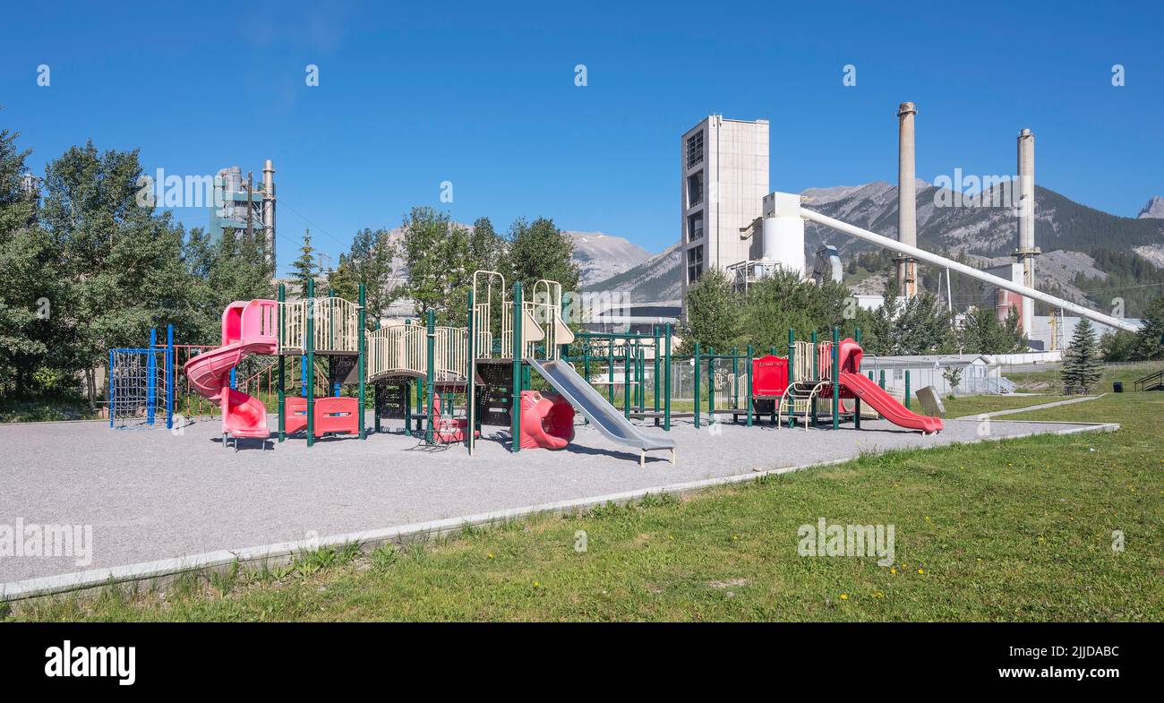 Une aire de jeux avec une usine de ciment en arrière-plan dans la ville d'Exshaw Banque D'Images