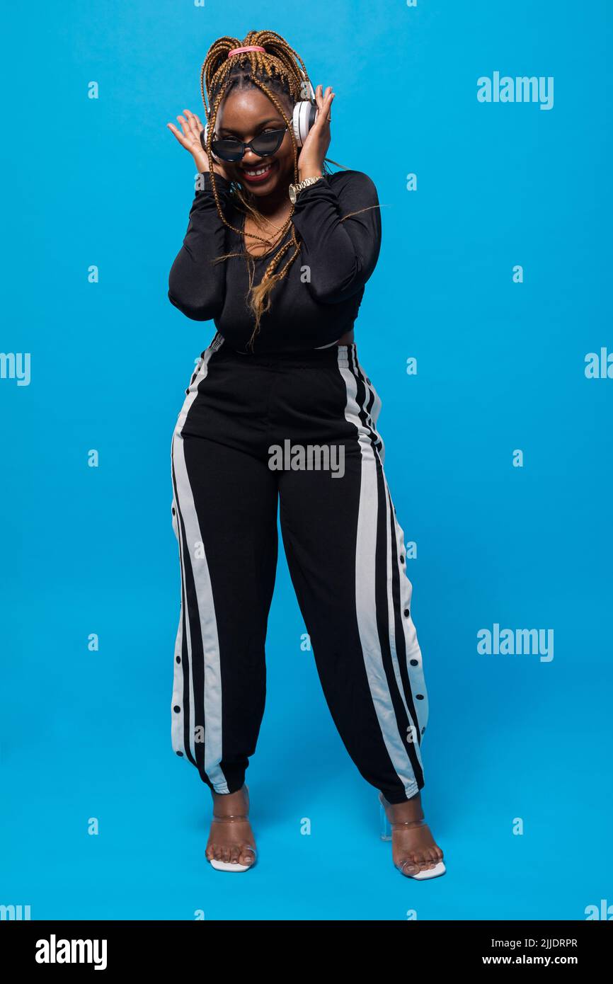 Sur fond bleu, une fille à la peau sombre écoute de la musique. Banque D'Images