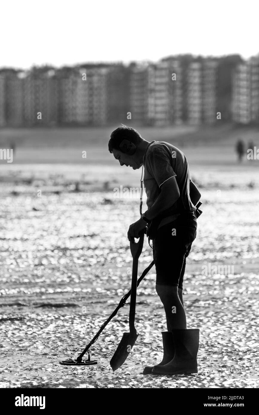 Homme avec détecteur de métal en bord de plage sur la plage de sable le long de la côte de la mer du Nord, tôt le matin en été pendant la saison des fêtes Banque D'Images