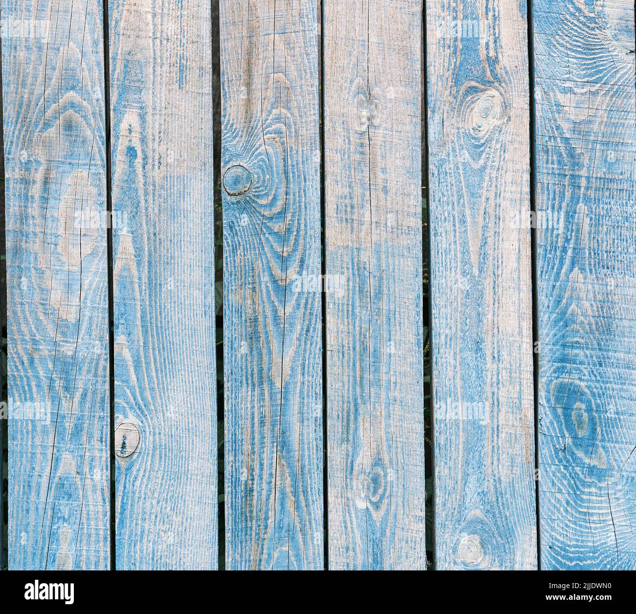 Le bleu de bois a décoloré les planches verticales d'une vieille clôture comme un arrière-plan rural abstrait. Banque D'Images