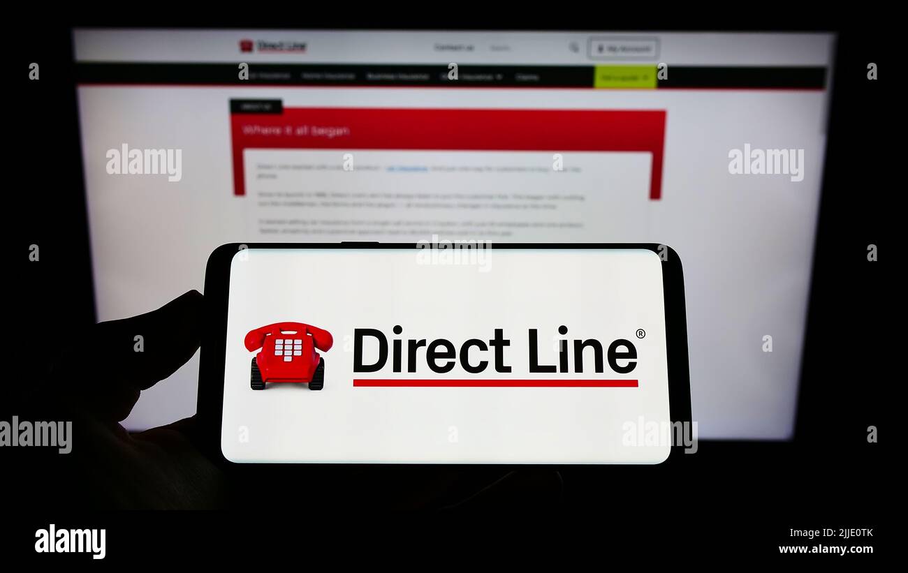 Personne tenant un smartphone avec le logo de la société U K Insurance Limited (Direct Line) à l'écran devant le site Web. Mise au point sur l'affichage du téléphone. Banque D'Images