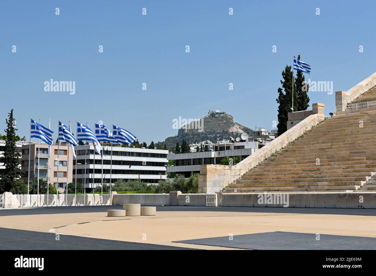 Athènes, Grèce - 2022 mai : vue panoramique des drapeaux nationaux grecs volant au stade olympique historique de la ville avec la colline de Lycabette au loin Banque D'Images