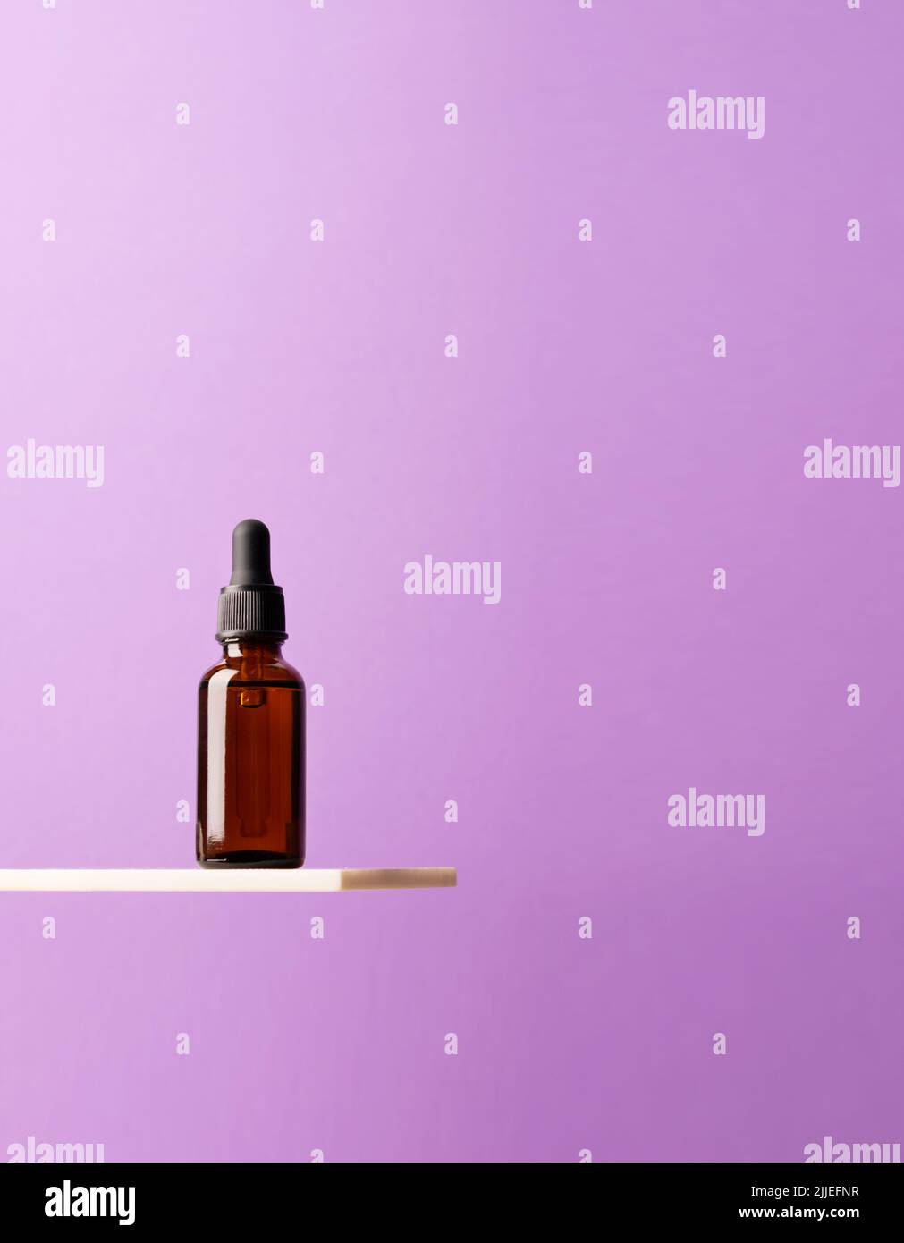 Bouteille de produit cosmétique, verre foncé avec étagère en marbre créatif pour pipettes, fond violet podium Banque D'Images