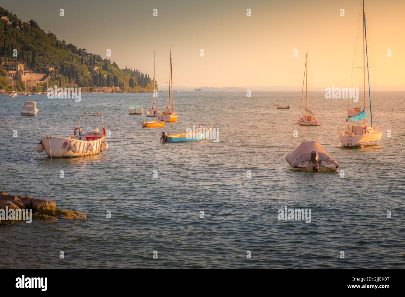 Voiliers flottant sur le lac de Garde au coucher du soleil doré, Malcesine, Italie Banque D'Images