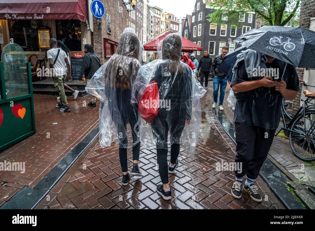 Touristes par temps pluvieux, portant des ponchos en plastique, dans la vieille ville d'Amsterdam, pays-Bas. Banque D'Images