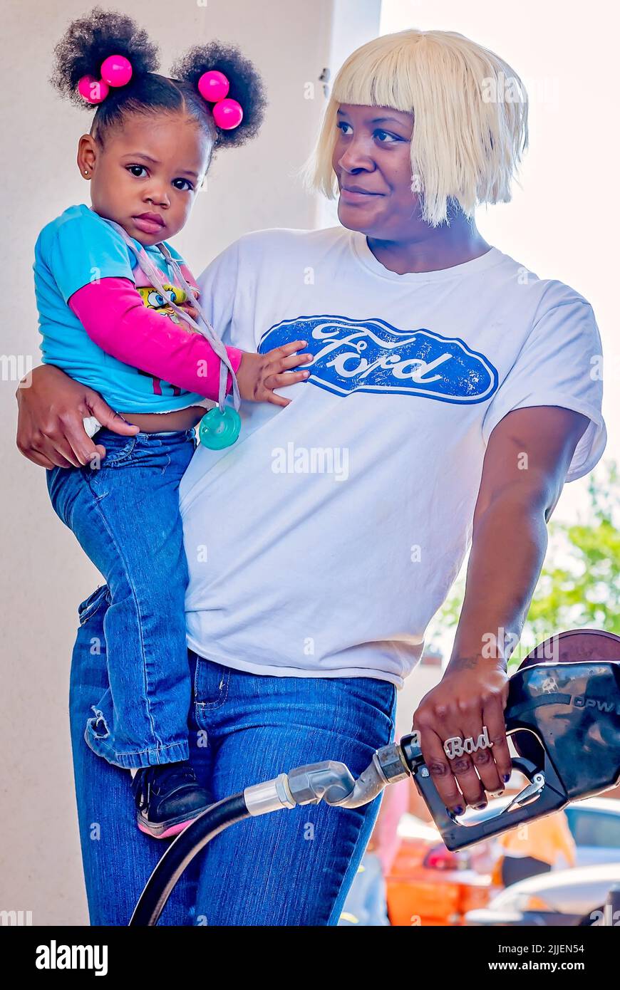 Une femme pompe du gaz comme elle tient sa fille, 14 avril 2011, à Columbus, Mississippi. Les prix de l'essence ont augmenté en 2011 en raison de la faiblesse du dollar américain. Banque D'Images
