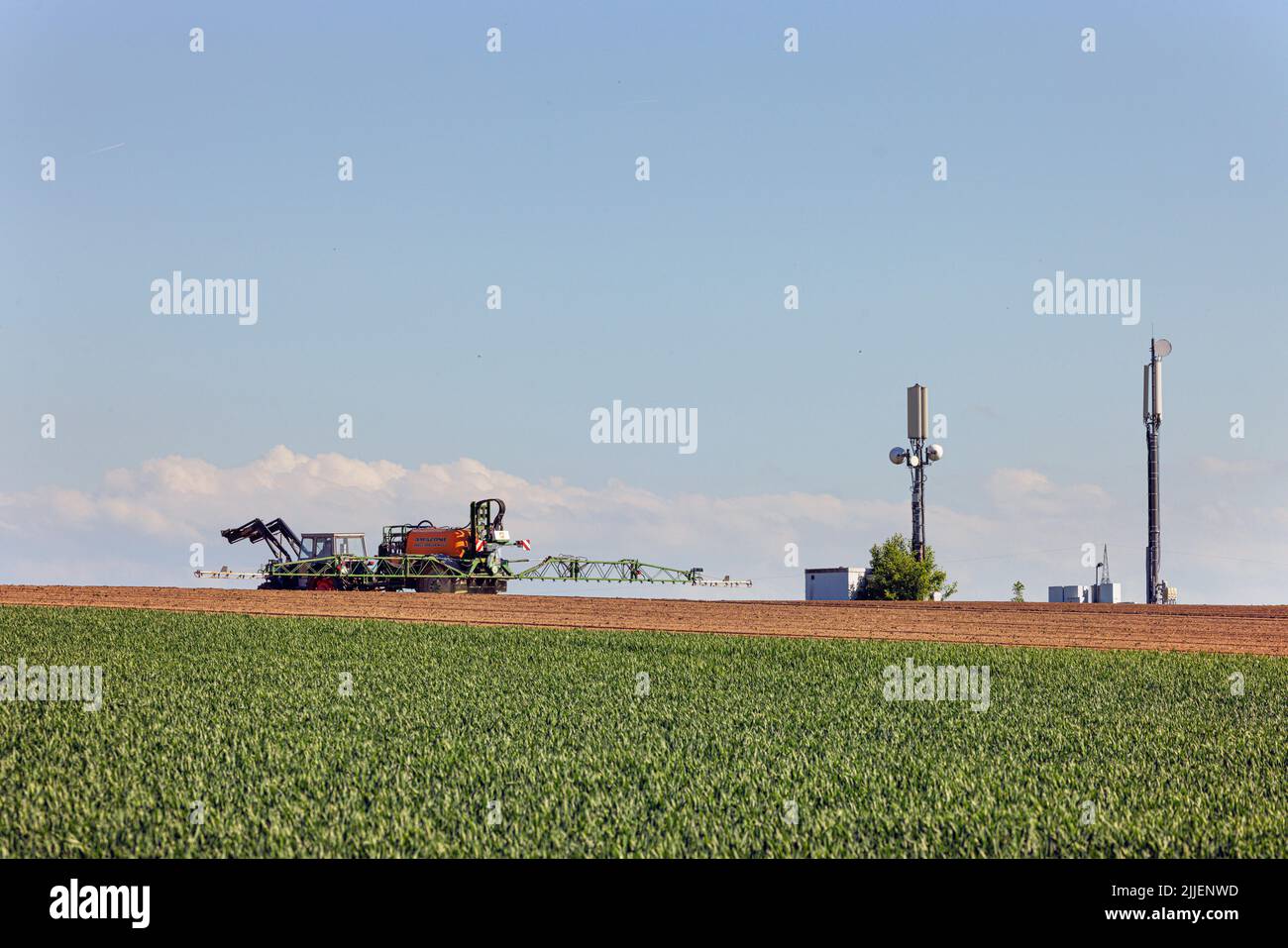 Agriculteur pulvérisant le champ avec du glyphosate, des mâts de téléphone mobile en arrière-plan, Allemagne, Bavière, Erdinger Moos Banque D'Images